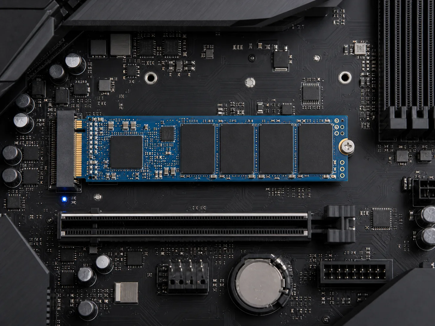 黒いマザーボードに青いNVMeストレージが取り付けられている真上からの写真